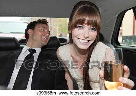 Picture - Newlywed couple in car with champagne. Fotosearch