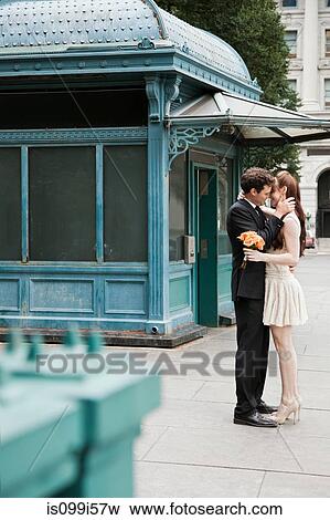 Newlywed couple kissing on city street View Large Photo Image Stock Photo - Newlywed couple kissing on city street. Fotosearch