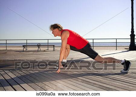 Stock Image - Runner stretching on promenade. Fotosearch