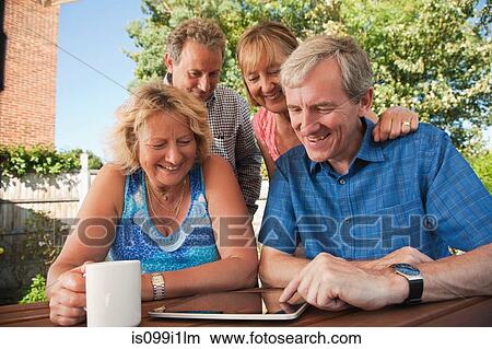 Senior and mature friends looking at digital tablet outdoors View Large Photo Image Picture - Senior and mature friends looking at digital tablet outdoors. Fotosearch