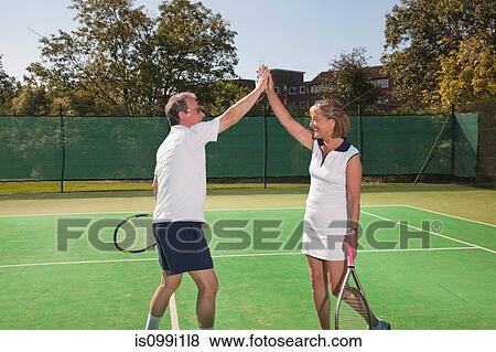 Senior couple hi-fiving on tennis court View Large Photo Image Stock Photo - Senior couple hi-fiving on tennis court. Fotosearch