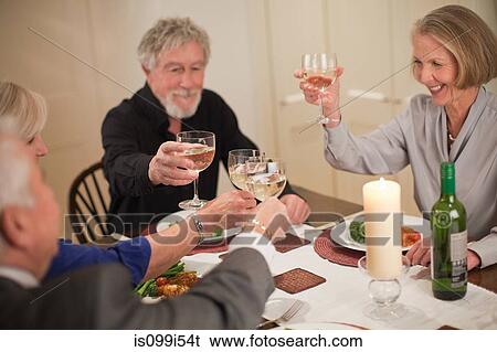 Senior friends raising glasses at dinner party View Large Photo Image Stock Photograph - Senior friends raising glasses at dinner party. Fotosearch