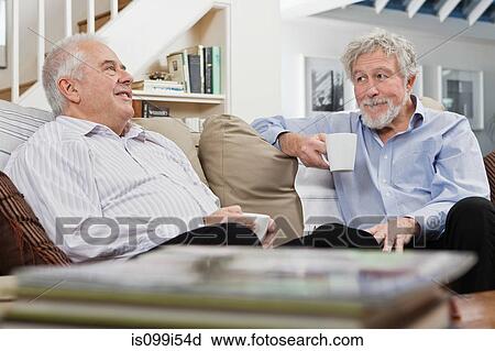 Stock Image - Senior male friends having coffee and chat. Fotosearch