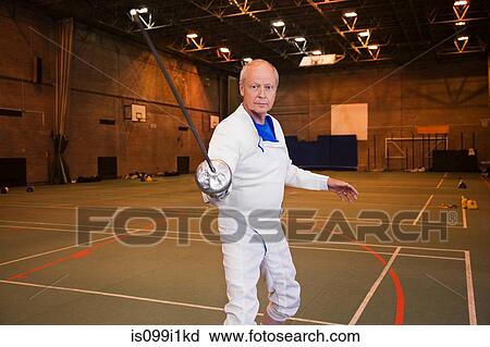 Stock Image - Senior man in fencing suit holding foil. Fotosearch