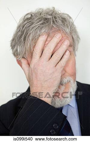 Stock Image - Senior man with hand covering face. Fotosearch