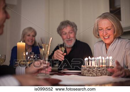 Stock Image - Senior woman and friends with birthday cake. Fotosearch