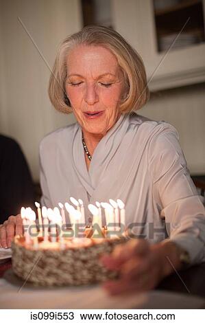 Senior woman blowing out candles on birthday cake View Large Photo Image Stock Image - Senior woman blowing out candles on birthday cake. Fotosearch