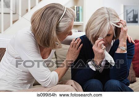 Stock Image - Senior woman comforting crying friend. Fotosearch