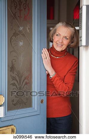 Stock Photograph - Senior woman opening front door. Fotosearch