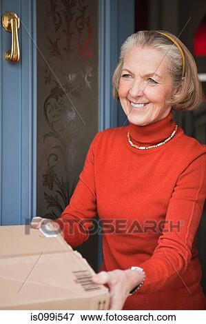 Senior woman receiving parcel at front door View Large Photo Image Stock Photo - Senior woman receiving parcel at front door. Fotosearch