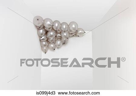 Stock Image - Silver balloons in corner of white room. Fotosearch