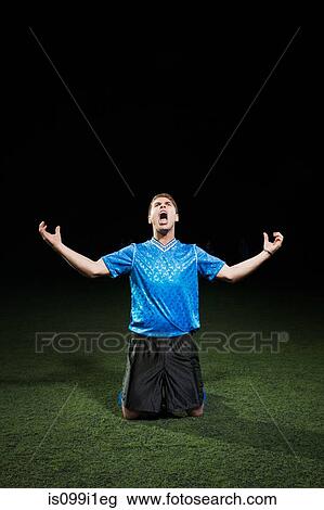 Soccer player kneeling on pitch with arms out View Large Photo Image Stock Image - Soccer player kneeling on pitch with arms out. Fotosearch