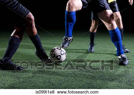 Stock Photo - Soccer players tackling on pitch, low section. Fotosearch