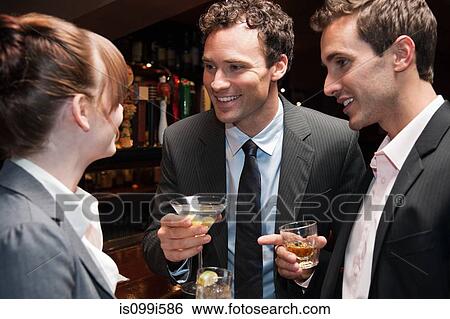 Two buisnessmen chatting to female colleague at bar View Large Photo Image Stock Photograph - Two buisnessmen chatting to female colleague at bar. Fotosearch
