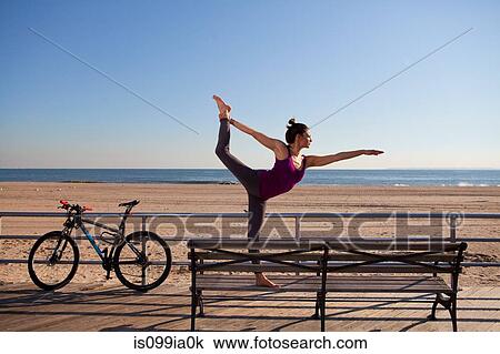 Stock Image - Woman in yoga pose on promenade. Fotosearch