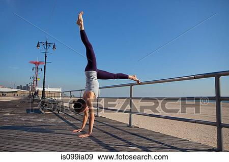 Stock Photo - Woman performing handstand on promenade. Fotosearch