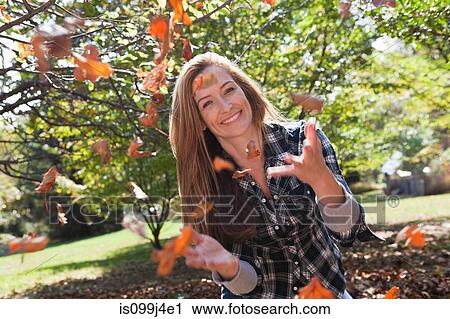 Woman throwing autumn leaves in the air View Large Photo Image Stock Image - Woman throwing autumn leaves in the air. Fotosearch