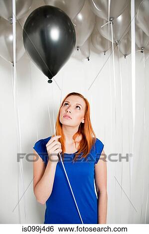 Young woman holding a black balloon View Large Photo Image Stock Photograph - Young woman holding a black balloon. Fotosearch