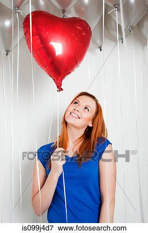 Stock Photo - Young woman holding a heart shaped balloon. Fotosearch