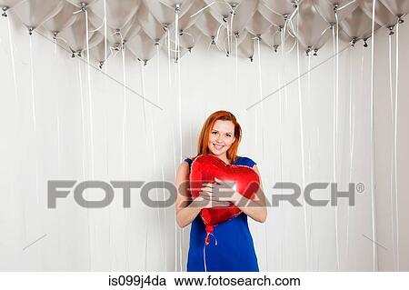 Young woman holding heart shaped balloon View Large Photo Image Stock Image - Young woman holding heart shaped balloon. Fotosearch