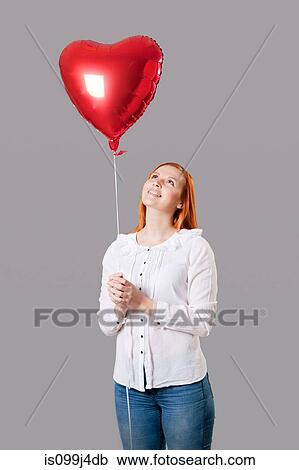Young woman holding heart shaped balloon View Large Photo Image Stock Image - Young woman holding heart shaped balloon. Fotosearch