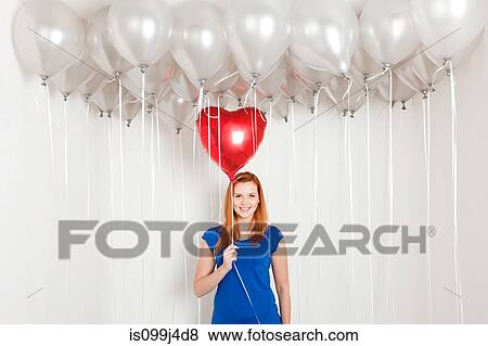Stock Photo - Young woman holding heart shaped balloon. Fotosearch