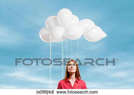 Stock Image - Young woman looking at thought bubble made of balloons. Fotosearch
