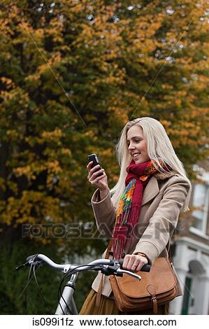 Young woman with bicycle, looking at cellphone View Large Photo Image Stock Photo - Young woman with bicycle, looking at cellphone. Fotosearch