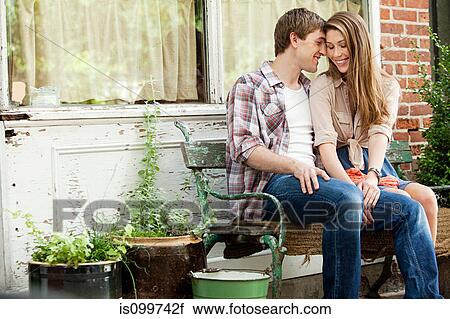 Stock Image - Affectionate young couple on bench. Fotosearch