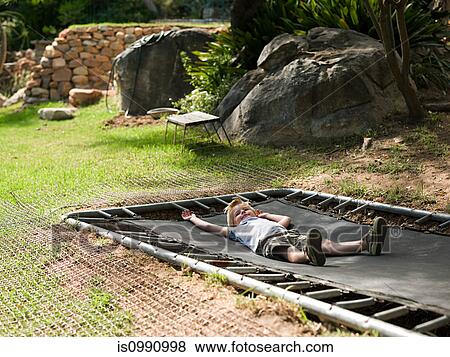 Boy lying on trampoline View Large Photo Image Stock Photo - Boy lying on trampoline. Fotosearch