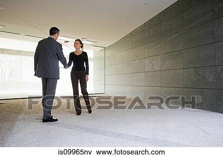 Businesspeople shaking hands in empty office View Large Photo Image Stock Photo - Businesspeople shaking hands in empty office. Fotosearch