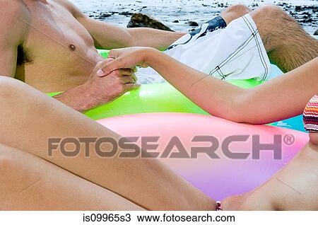 Couple in inflatable rings holding hands View Large Photo Image Stock Image - Couple in inflatable rings holding hands. Fotosearch