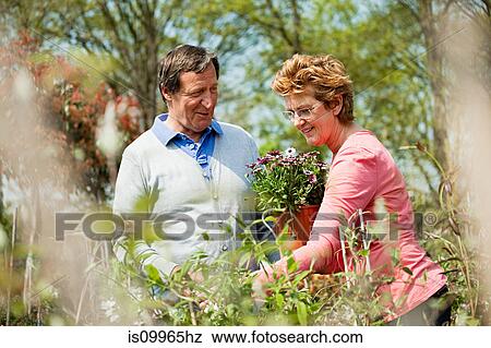 Stock Photo - Couple looking at plants at garden center. Fotosearch