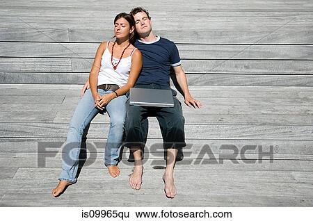 Couple lying on decking with laptop View Large Photo Image Stock Photograph - Couple lying on decking with laptop. Fotosearch