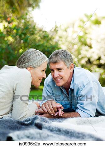 Couple lying on picnic blanket in garden View Large Photo Image Stock Image - Couple lying on picnic blanket in garden. Fotosearch