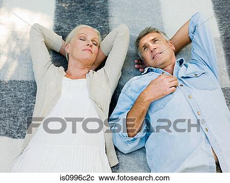 Stock Image - Couple lying on picnic blanket in garden. Fotosearch