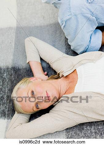 Stock Image - Couple lying on picnic blanket in garden. Fotosearch