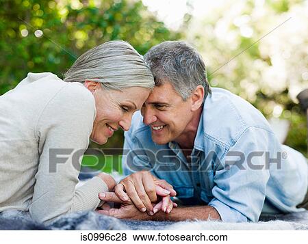 Couple lying on picnic blanket in garden View Large Photo Image Stock Photo - Couple lying on picnic blanket in garden. Fotosearch