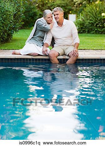 Stock Photography - Couple sitting at poolside in garden. Fotosearch