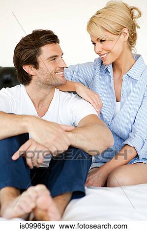 Stock Photo - Couple sitting on bed, portrait. Fotosearch