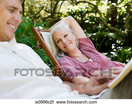 Stock Image - Couple sitting on deckchairs in garden. Fotosearch