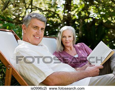 Stock Image - Couple sitting on deckchairs in garden. Fotosearch