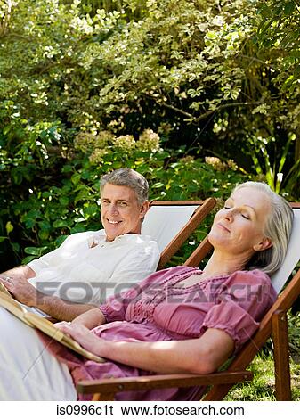 Stock Photograph - Couple sitting on deckchairs in garden. Fotosearch