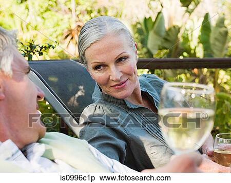 Couple sitting on garden chairs with wine View Large Photo Image Stock Photography - Couple sitting on garden chairs with wine. Fotosearch