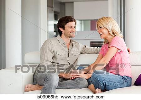 Couple sitting on sofa holding hands View Large Photo Image Stock Image - Couple sitting on sofa holding hands. Fotosearch