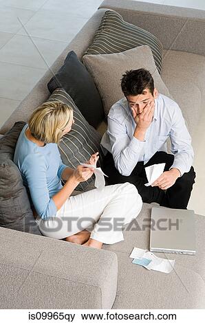 Couple sitting on sofa with financial problems View Large Photo Image Stock Photo - Couple sitting on sofa with financial problems. Fotosearch