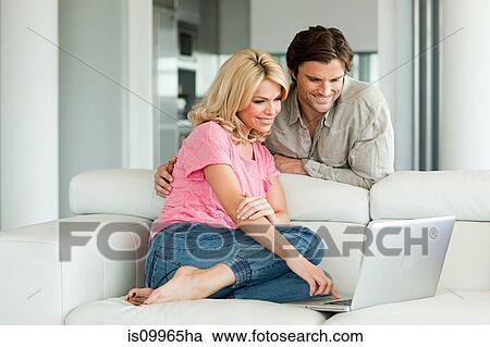 Couple using laptop at home View Large Photo Image Stock Image - Couple using laptop at home. Fotosearch