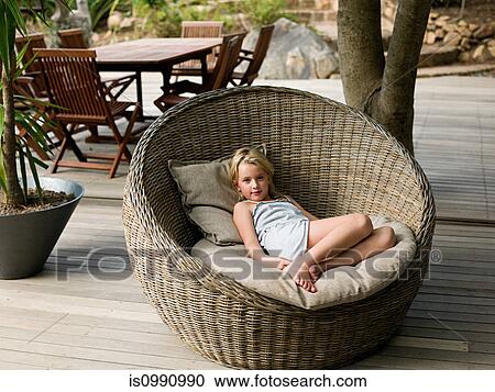 Girl sitting in wicker chair, portrait View Large Photo Image Stock Image - Girl sitting in wicker chair, portrait. Fotosearch