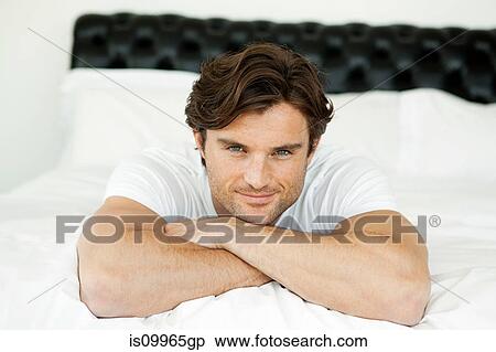 Man lying on bed, portrait View Large Photo Image Stock Photography - Man lying on bed, portrait. Fotosearch