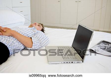 Man lying on bed with laptop View Large Photo Image Stock Photography - Man lying on bed with laptop. Fotosearch